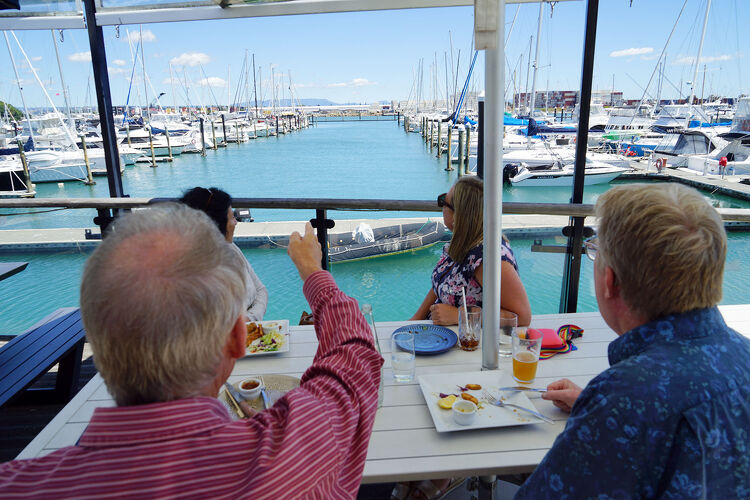 People enjoying lunch at a waterfront restaurant overlooking Tauranga Marina in New Zealand's Bay of Plenty.